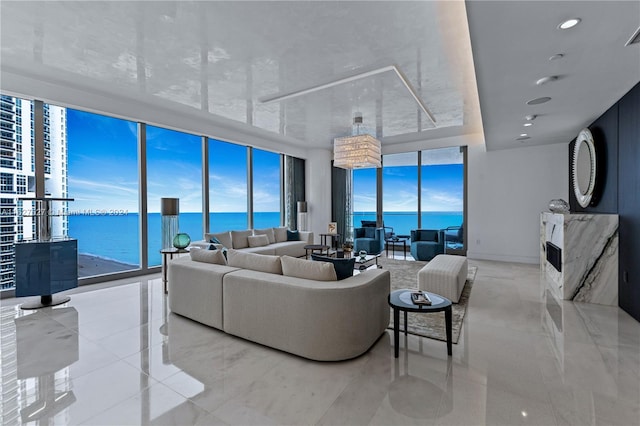 living room featuring light tile patterned flooring, a water view, and a wall of windows