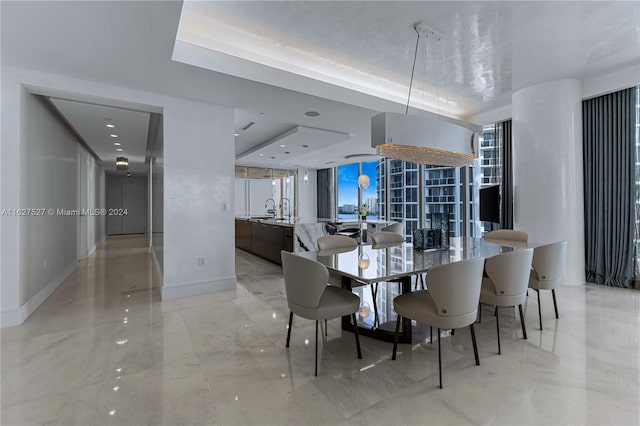 tiled dining area with a tray ceiling