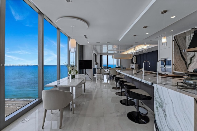 kitchen with light stone counters, expansive windows, a breakfast bar area, and light tile patterned floors