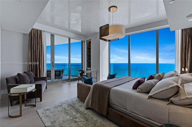 bedroom featuring access to exterior, a water view, and hardwood / wood-style floors