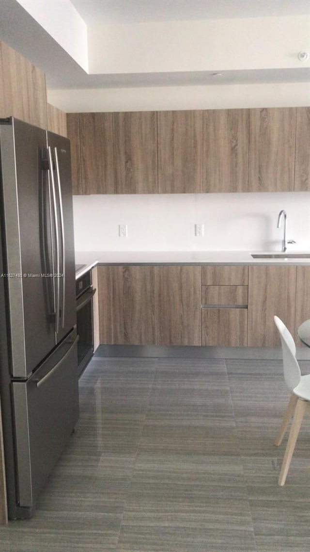 kitchen with oven, stainless steel refrigerator, and sink