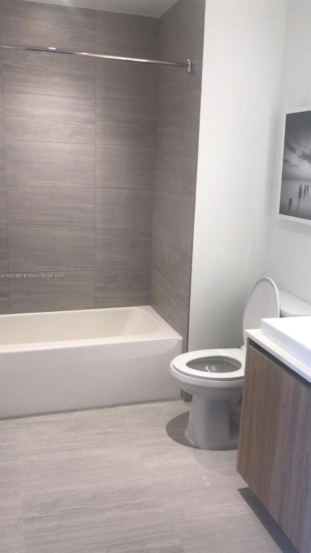 full bathroom featuring tile patterned floors, vanity, tiled shower / bath, and toilet