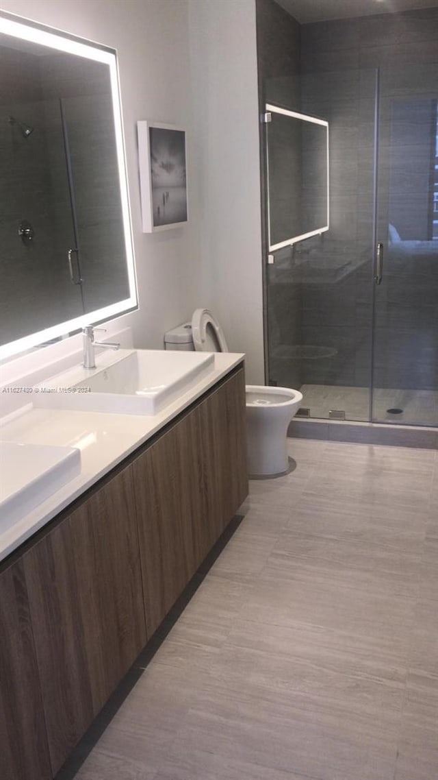 bathroom featuring a shower with shower door, toilet, and vanity