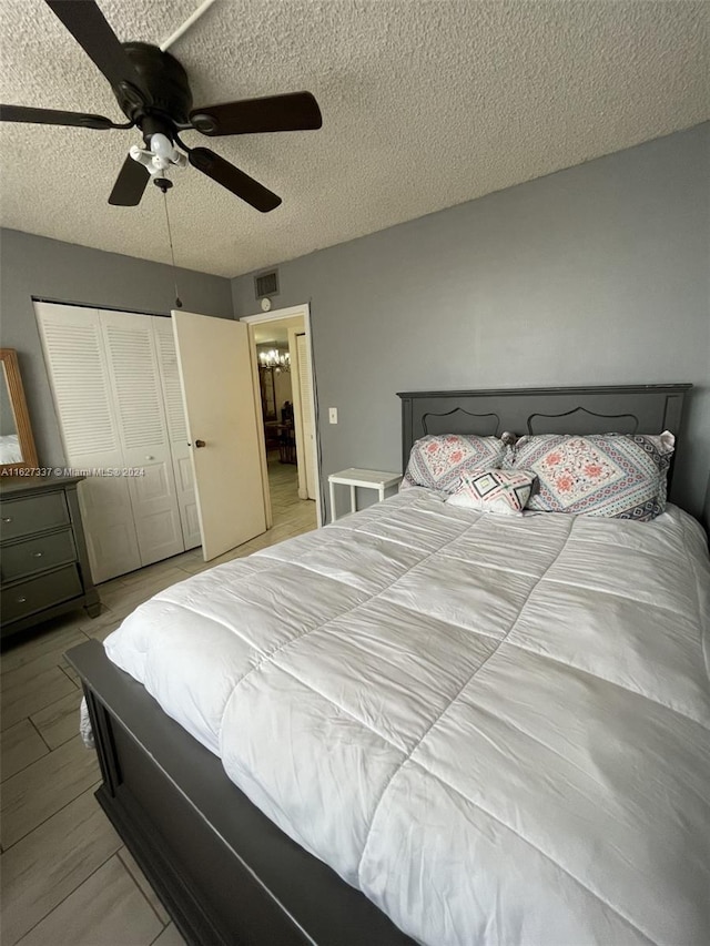 bedroom with light wood-type flooring, a textured ceiling, a closet, and ceiling fan