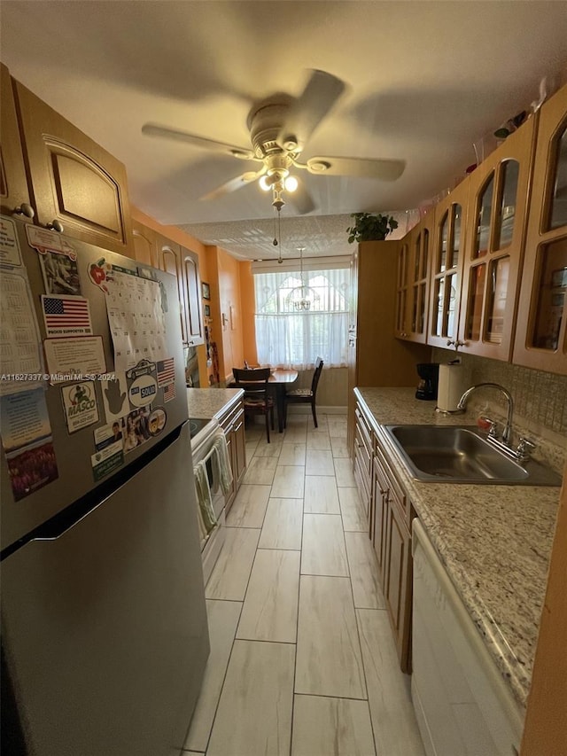 kitchen with decorative backsplash, stainless steel appliances, ceiling fan, sink, and hanging light fixtures