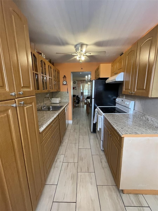 kitchen with light stone countertops, appliances with stainless steel finishes, tasteful backsplash, ceiling fan, and sink