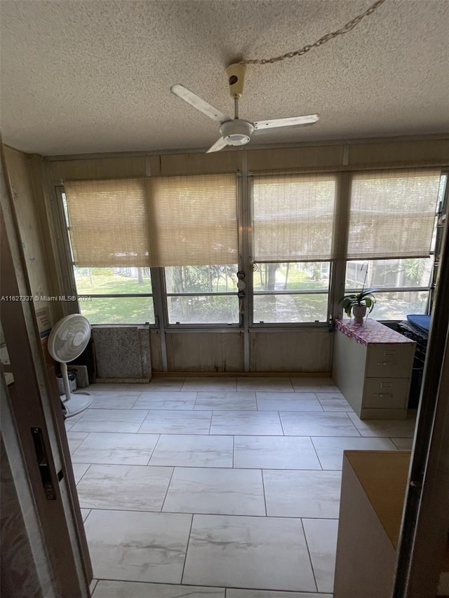 unfurnished sunroom with ceiling fan