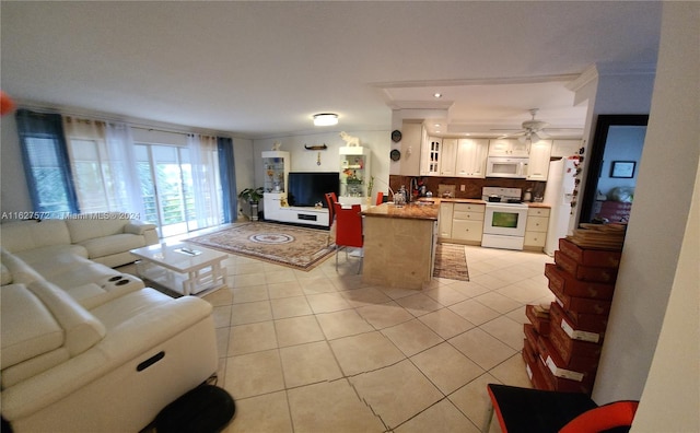 tiled living room with ceiling fan, ornamental molding, and sink