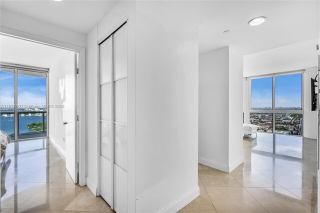 corridor with a water view, a barn door, light tile patterned floors, and a wealth of natural light