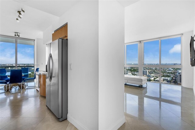 interior space with floor to ceiling windows, a healthy amount of sunlight, and stainless steel refrigerator with ice dispenser