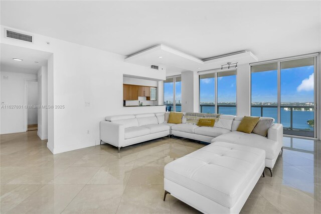 living room with a water view, plenty of natural light, and a wall of windows