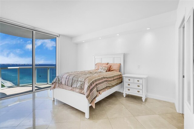 bedroom with multiple windows, light tile patterned floors, access to exterior, and a wall of windows