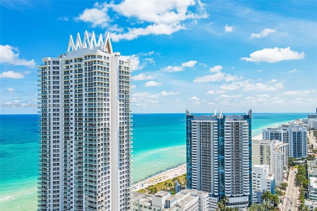 view of building exterior featuring a water view and a beach view