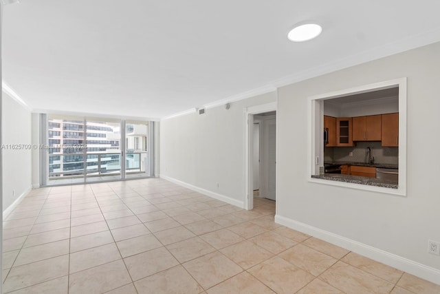 unfurnished room featuring light tile patterned floors, crown molding, a wall of windows, and sink