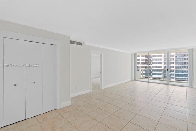 interior space with crown molding, a wall of windows, and light tile patterned floors