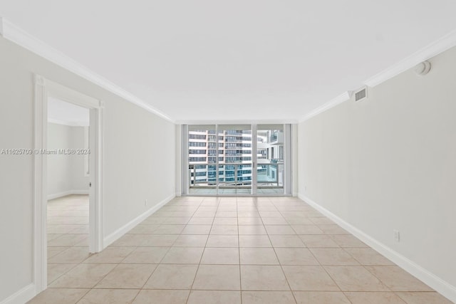 tiled spare room with ornamental molding and expansive windows