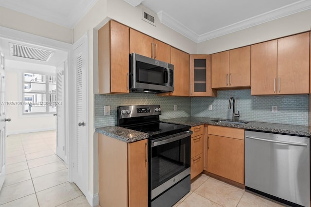 kitchen featuring stainless steel appliances, backsplash, light tile patterned flooring, dark stone countertops, and sink