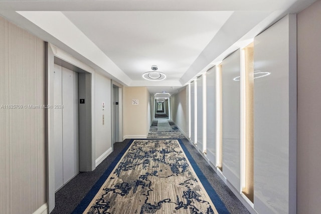 hall featuring a tray ceiling and elevator