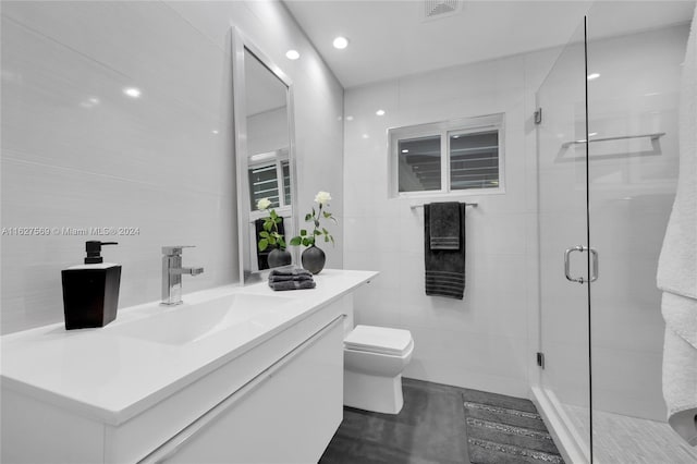 bathroom with vanity, tile patterned floors, walk in shower, tile walls, and toilet