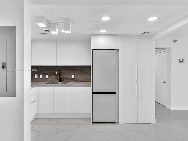 kitchen with sink, built in refrigerator, electric panel, white cabinets, and backsplash