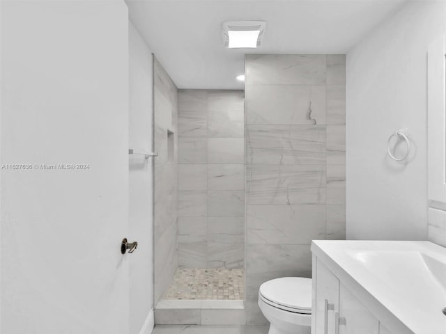 bathroom featuring vanity, toilet, and a tile shower