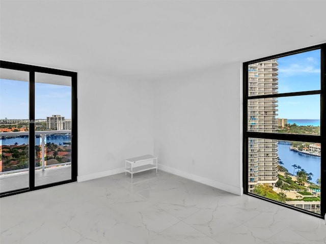 empty room with a water view, floor to ceiling windows, and a wealth of natural light