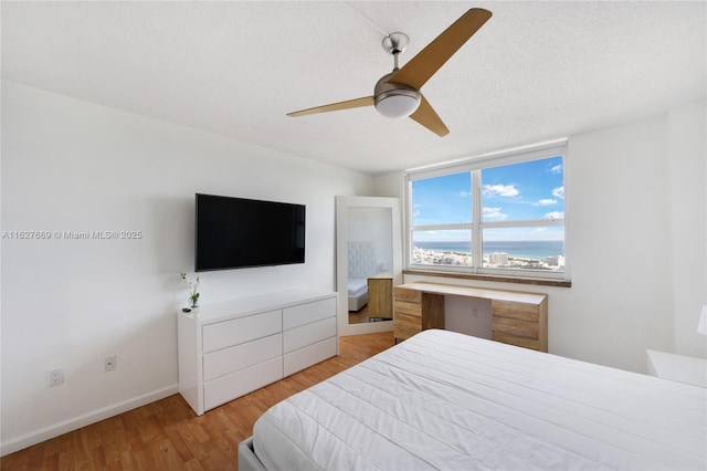 bedroom with ceiling fan, a textured ceiling, and light wood-type flooring