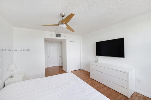 bedroom featuring ceiling fan, a closet, a textured ceiling, and light wood-type flooring