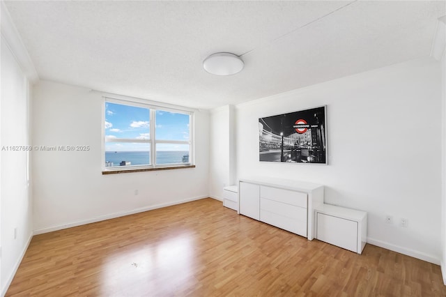 empty room featuring hardwood / wood-style floors, a water view, and crown molding