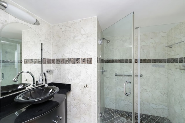 bathroom featuring vanity, a shower with door, and tile walls