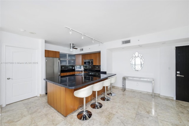 kitchen with a kitchen breakfast bar, ceiling fan, and appliances with stainless steel finishes