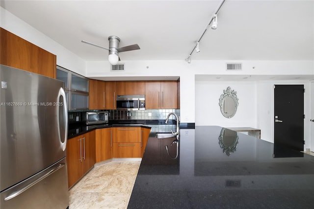 kitchen featuring rail lighting, sink, ceiling fan, tasteful backsplash, and stainless steel appliances