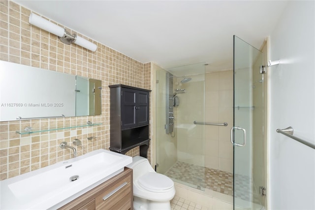 bathroom with backsplash, vanity, a shower with door, tile walls, and toilet