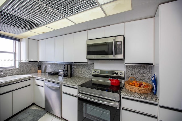 kitchen featuring stainless steel appliances, backsplash, and white cabinets