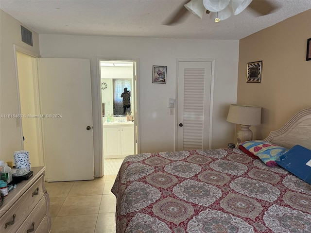 tiled bedroom featuring ceiling fan, a textured ceiling, and ensuite bathroom