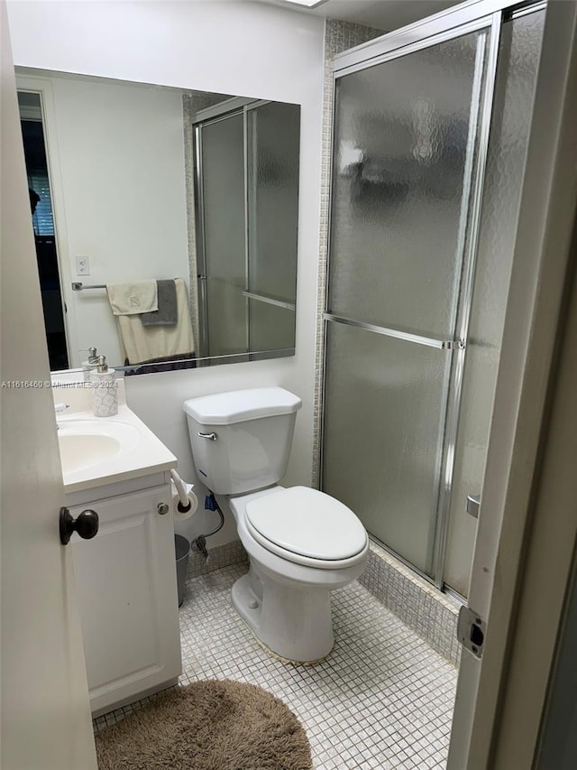 bathroom featuring tile patterned flooring, vanity, a shower with door, and toilet