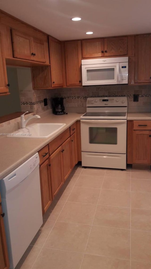 kitchen with sink, light tile patterned floors, backsplash, and white appliances