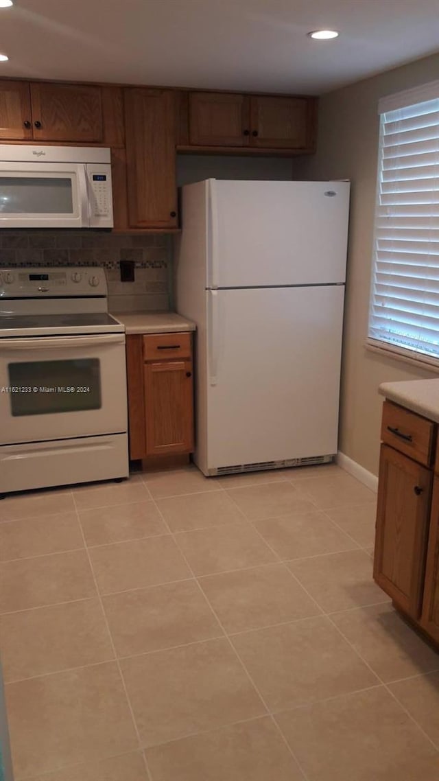 kitchen featuring decorative backsplash, white appliances, and light tile patterned floors