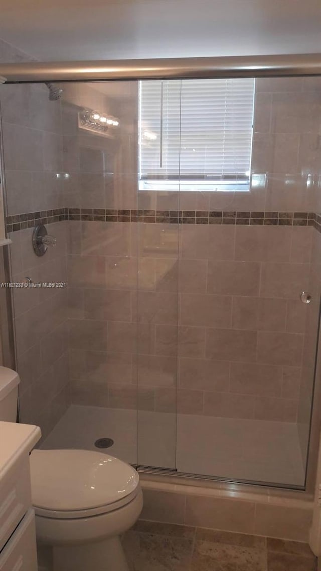 bathroom featuring tile patterned floors, vanity, a shower with door, and toilet