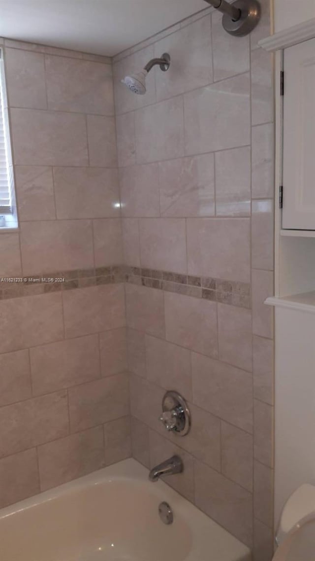 bathroom with tiled shower / bath combo and toilet