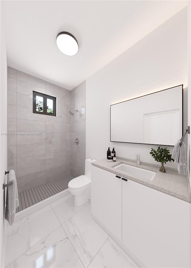 bathroom featuring vanity, toilet, a tile shower, and tile patterned flooring