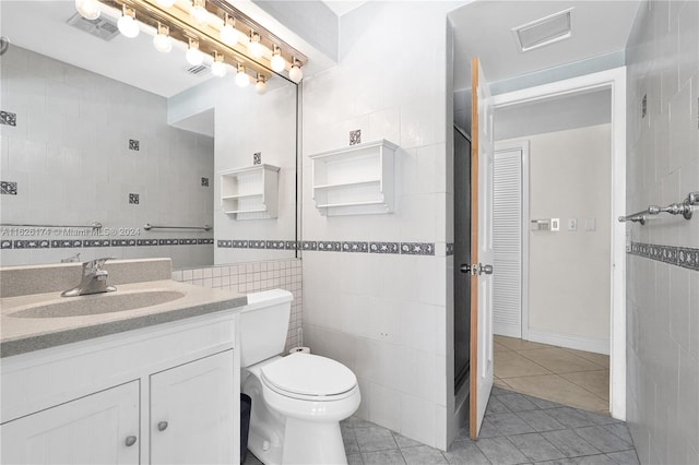 bathroom with tile walls, vanity, toilet, and tile patterned flooring