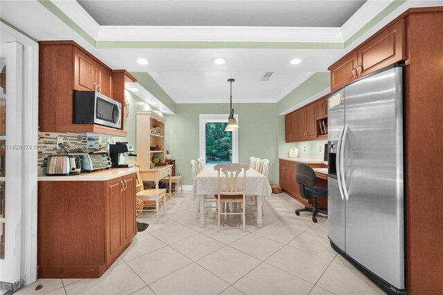 kitchen featuring crown molding, stainless steel appliances, light tile patterned floors, decorative backsplash, and decorative light fixtures