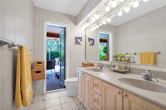 bathroom featuring tile walls, double sink vanity, toilet, and tile patterned floors