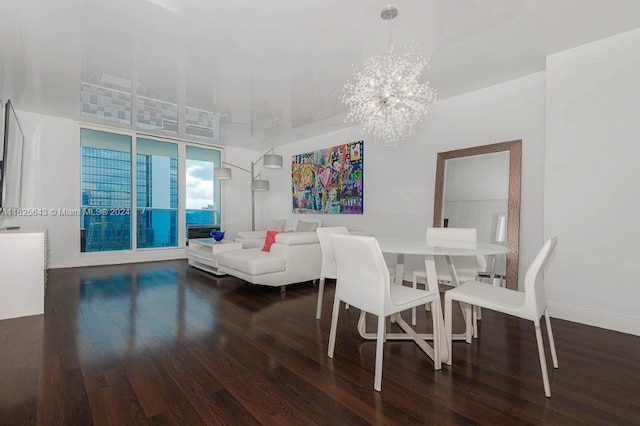 dining space with a high ceiling, dark hardwood / wood-style floors, and an inviting chandelier