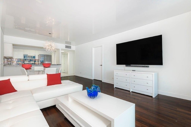 living room with dark hardwood / wood-style flooring and a chandelier