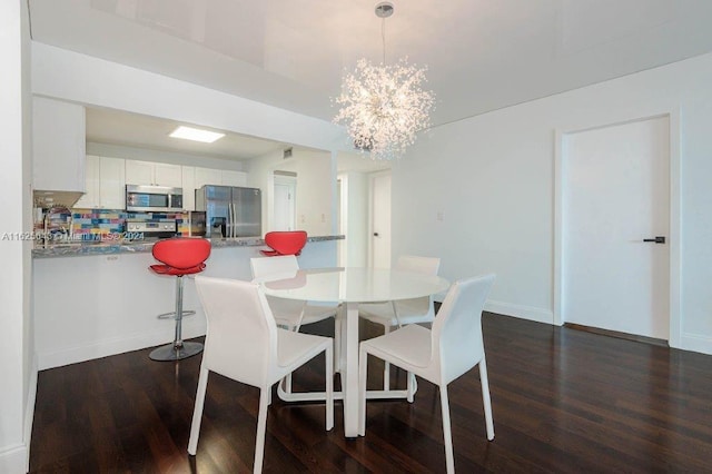 dining room with dark wood-type flooring and a notable chandelier