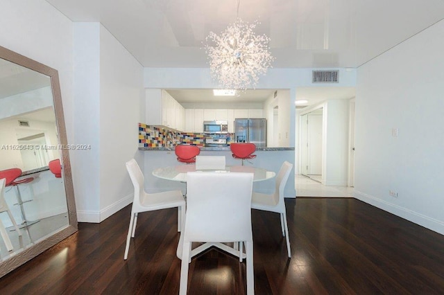 dining space with dark hardwood / wood-style floors and an inviting chandelier