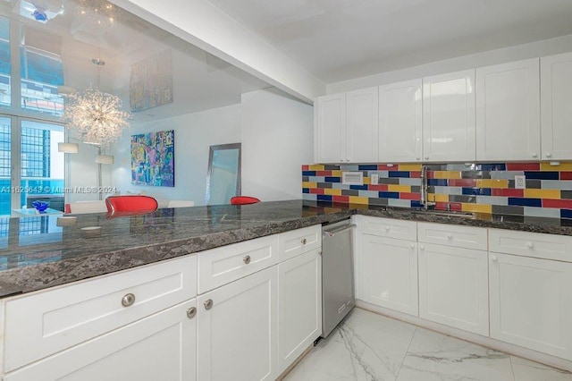 kitchen featuring pendant lighting, decorative backsplash, dark stone countertops, and white cabinetry