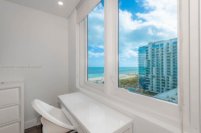 bathroom with a view of the beach, a water view, and hardwood / wood-style flooring